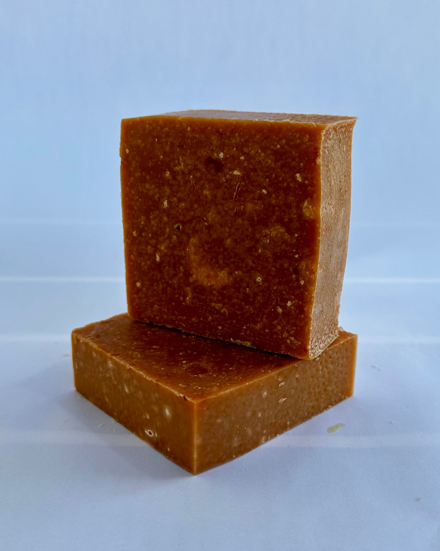 Two reddish soap bars stacked on a light background