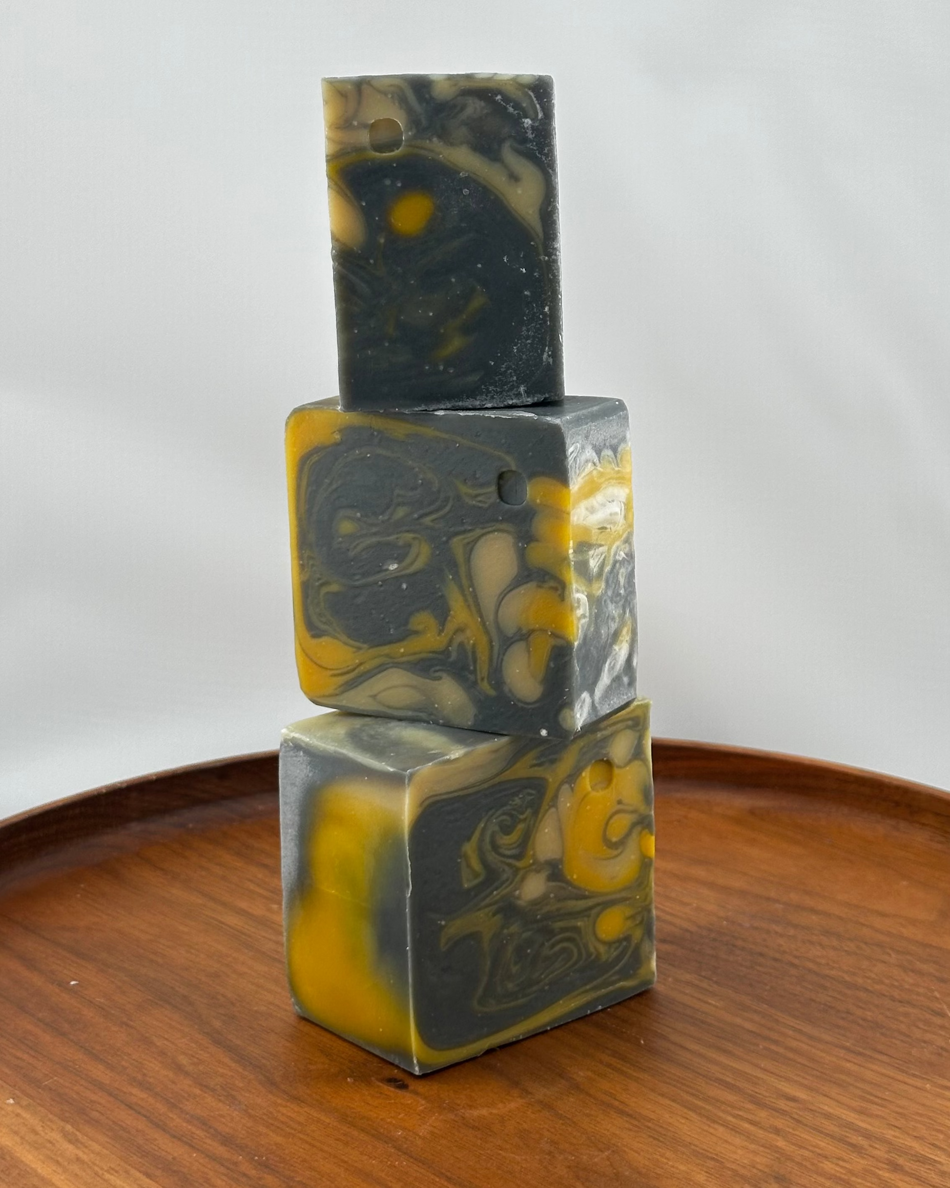 Three stacked soap bars with a marbled pattern on a wooden surface.