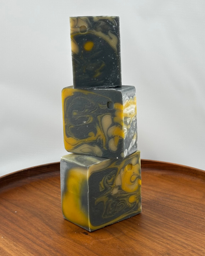 Three stacked soap bars with a marbled pattern on a wooden surface.