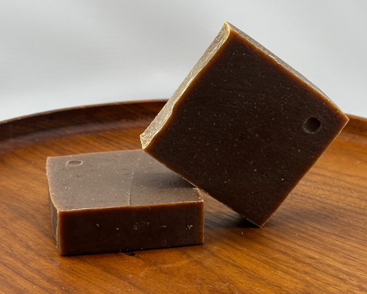 Two bars of Golden Hour soap on a wooden plate with a white background